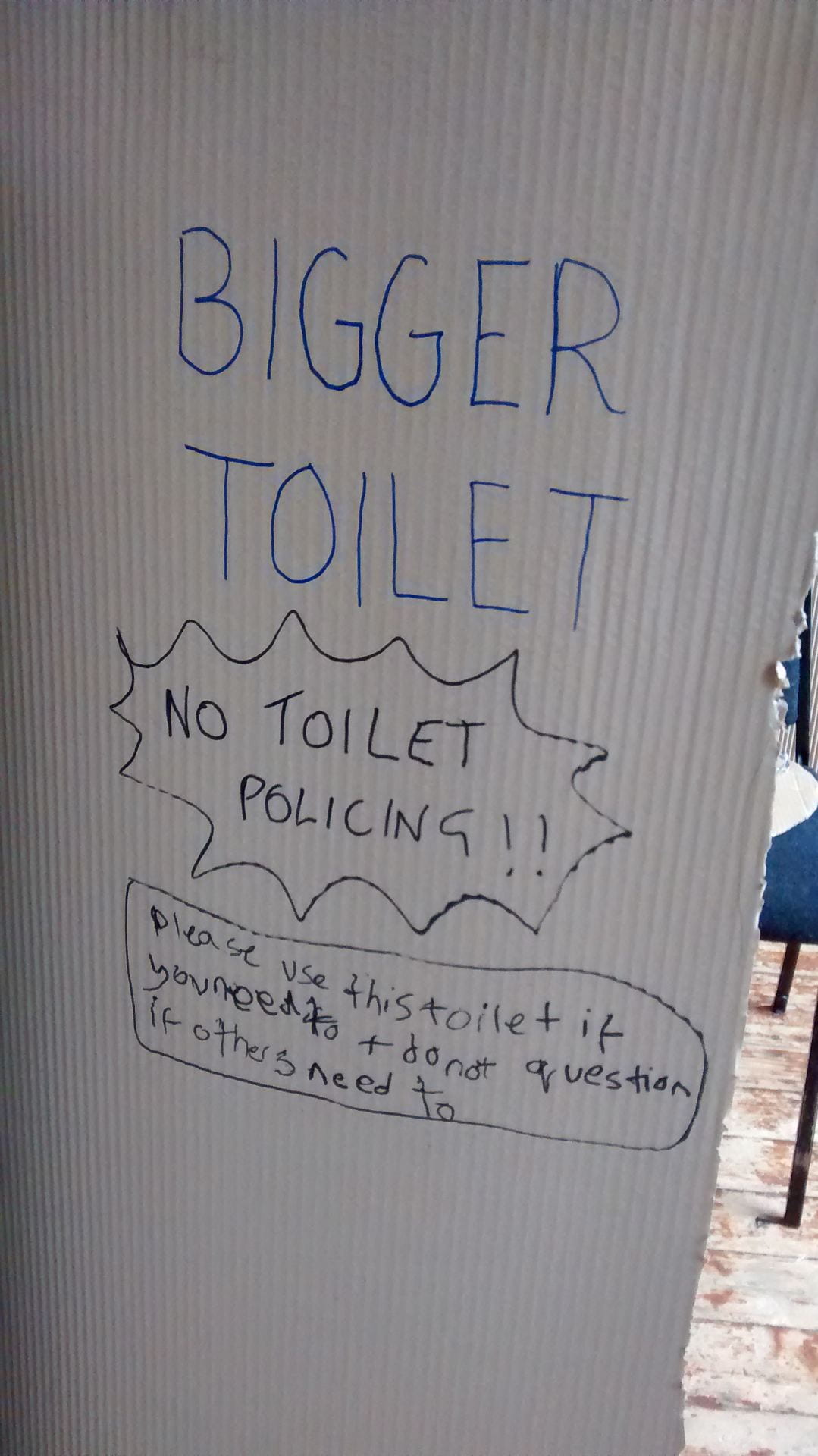 A photo of a large piece of brown corrugated cardboard. On it, a person taking part in an 'Around the Toilet' workshop has written 'TOILET. NO TOILET POLICING. Please use this toilet if you need to and don't question if others need to.'